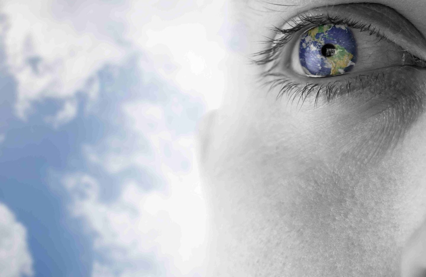close-up-eye-looking-up-against-bright-blue-sky-with-clouds